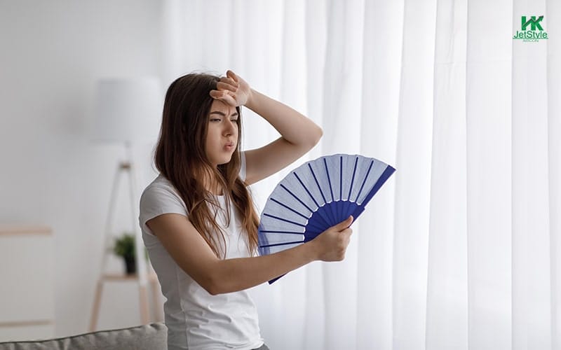 A Person Holding A Fan While Experiencing Hot Indoor Temperature