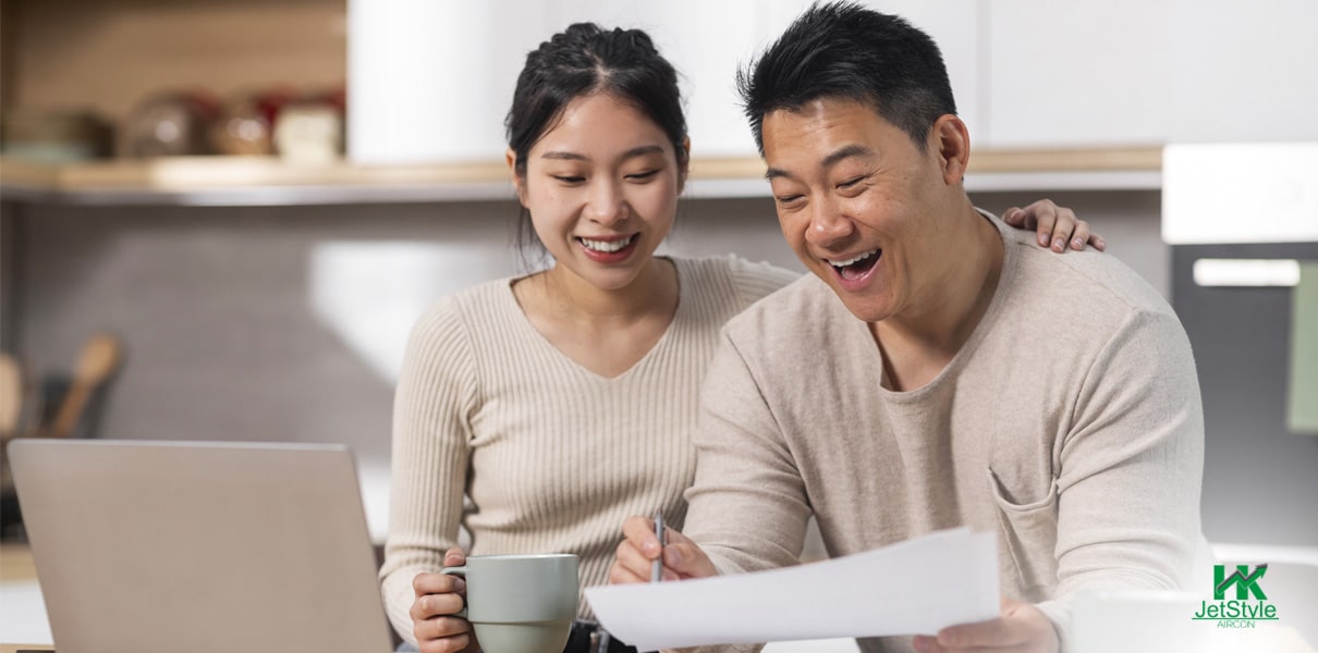 Couple smiling while looking at utility bills-Aircon chemical overhaul Singapore