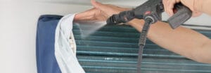 Aircon Technician Cleaning The Condenser Unit Of An Aircon